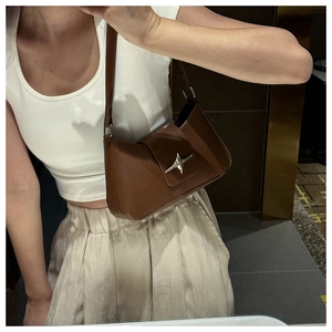 Détail d'un sac sous les bras marron foncé avec une boucle en métal argenté en étoile