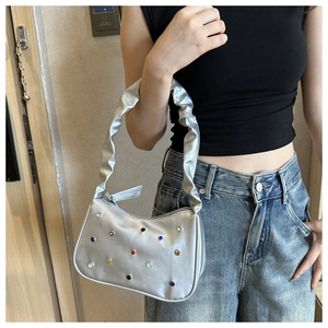 Silberne Achseltasche mit bunten Nieten und Raffriemen an der Schulter