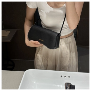Mirror selfie showing the black textured crossbody bag with gold FASHION & BAGS logo