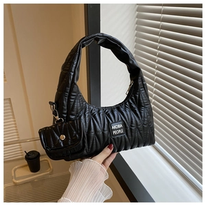 Détail d'un sac hobo noir matelassé avec motif à losanges et un mini porte-monnaie suspendu