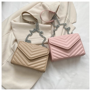 Detail of quilted V-stitch crossbody bags in khaki and pink on a stylish blazer