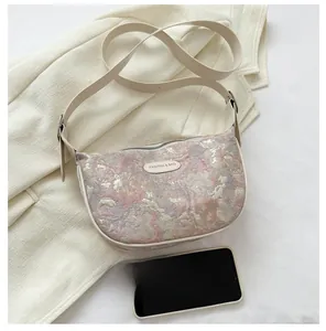 Detail of floral jacquard fabric texture and leather strap on this crescent bag