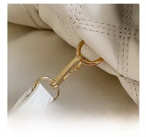 Détail du fermoir doré poli et de la texture en cuir blanc matelassé du sac à main