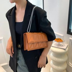 Caramel quilted geometric crossbody bag with silver chain strap worn by a model