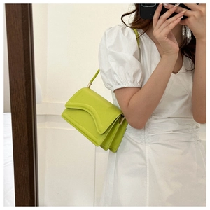 Detail of avocado green crossbody bag with unique wavy flap and rectangular design