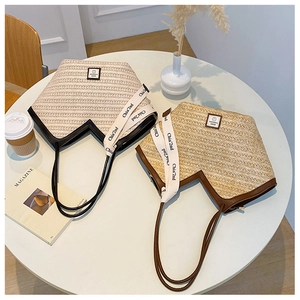 Detail view of woven straw tote bags with leather trim and decorative straps on a table