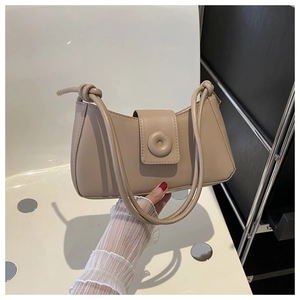 Detail of minimalist beige leather underarm bag with knot strap and round buckle clasp