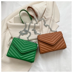 Detail of chevron quilted faux leather bags in green and brown with silver chain straps
