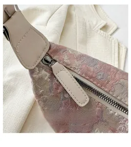 Detail of smooth metal zipper and floral embroidery on a silk crossbody dumpling bag