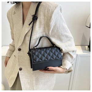 Detail einer schwarzen Stepptasche mit verstellbarem Knotenschultergurt am Model getragen