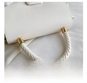 Détail de la poignée en cuir blanc tressé avec attaches métalliques dorées du sac à main