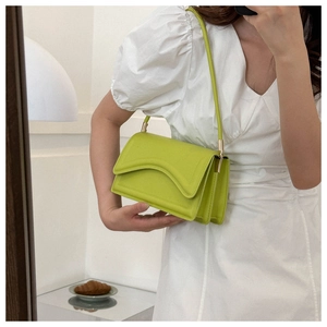 Detail of neon green crocodile texture handbag with wavy flap and golden hardware