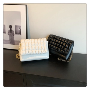 Close-up of black and white quilted puff shoulder bags with gold chain straps