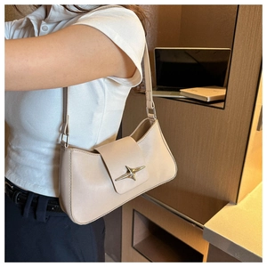 Détail d'un sac sous le bras en cuir beige avec une boucle métallique dorée en forme d'étoile