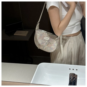 Mirror selfie showing iridescent brocade crescent bag with a white leather strap