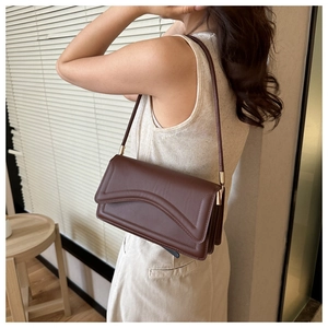 Detailed side view of a brown rectangular leather crossbody bag with overlapping flap design
