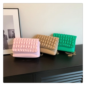 Detailed view of bubble texture flap bags in pink, beige, and green with gold chain straps