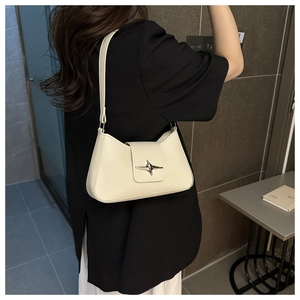 Détail d'un sac sous le bras blanc crème avec une boucle étoile argentée et une bandoulière