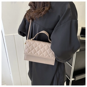 Detailansicht einer kaffeebraunen Stepptasche aus PU-Leder, von einem Model getragen
