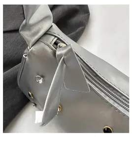 Details einer silbernen Metallic-Tasche mit glattem Reißverschluss und bunten Steinen