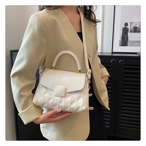 Détail du sac bandoulière blanc matelassé avec poignée tressée sur tenue de mannequin