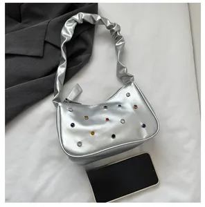 Detailansicht der silbernen sichelförmigen Tasche mit bunten Strasssteinen und gerafftem Griff