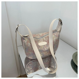 Detail view of pink floral jacquard fabric texture and leather strap on dumpling bag
