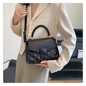 Détail du sac à main noir matelassé avec poignée tressée épaisse et boucles dorées chic