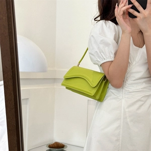 Minimalist neon green faux leather handbag with wave stitching shown in a mirror selfie
