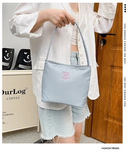 Detail view of light blue nylon bag with pink letter embroidery and a shoulder strap