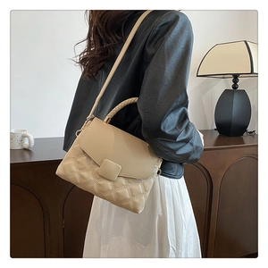 Gros plan d'un sac bandoulière beige matelassé avec poignée tressée dans un cadre élégant