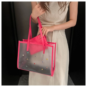 Detail of transparent tote bag featuring pink lining and colorful rhinestone embellishments