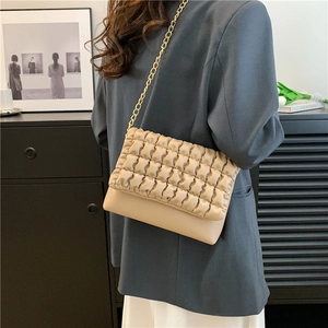 Chic beige quilted puffer crossbody bag with gold chain strap worn by a model