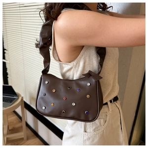 Details einer braunen Leder-Schultertasche mit bunten Kristallen und Faltenriemen