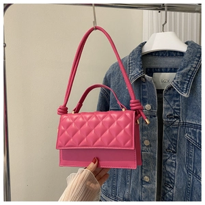Nahaufnahme einer pinkfarbenen Stepptasche mit goldener Hardware und geknotetem Riemen