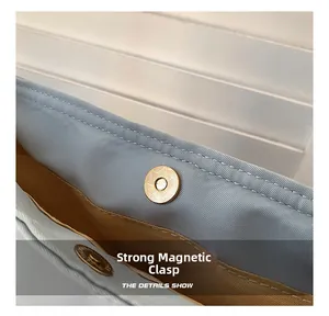 Detailed macro view of a strong gold magnetic buckle on a light blue nylon bag texture