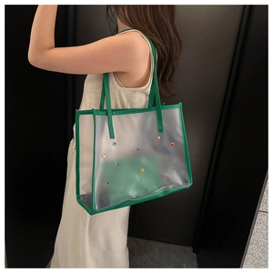 Detail of green PVC tote bag featuring vibrant colored studs and stylish shoulder strap