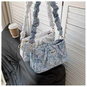 Détail de sacs à bandoulière froncés avec chaînes métalliques florales en blanc et bleu
