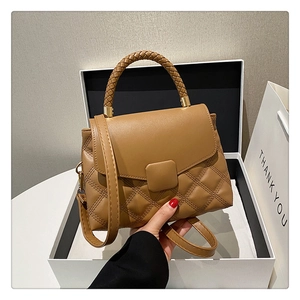 Détail du sac matelassé marron avec poignée tressée, fermoir en métal et coffret cadeau
