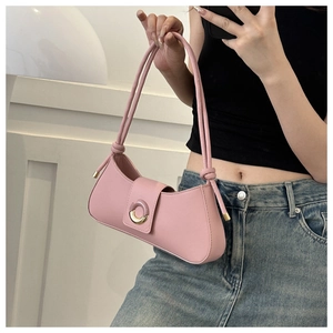 Detail of light pink underarm bag featuring knotted shoulder straps and round gold buckle