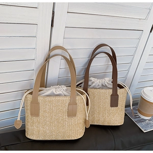 Detail view of woven straw handbags with leather handles and canvas drawstring liners