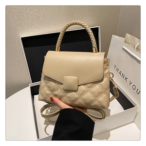 Détail du sac à bandoulière matelassé beige avec poignée tissée en emballage cadeau