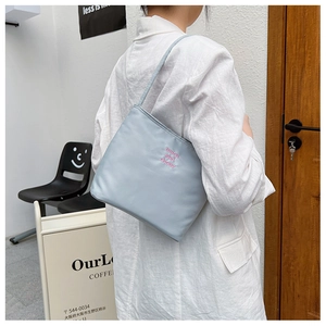 Close-up of light blue nylon tote bag with pink milen and chony embroidery details