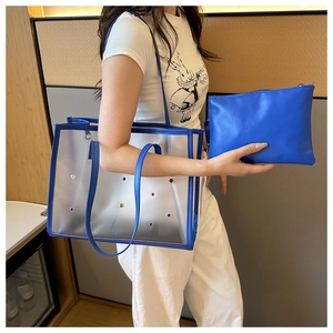 Detail view of transparent PVC tote with blue leather trim and colorful rhinestone studs