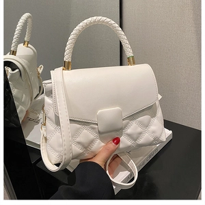 Détail du sac à main blanc matelassé avec poignée tressée et finitions dorées