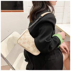 Detailed side view of floral crossbody bag with chain strap worn on black blazer