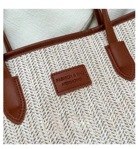 Detail of herringbone woven fiber straw tote with dark brown leather straps and stitching