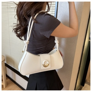 Close-up of white leather underarm bag with decorative metal buckle on a shoulder model