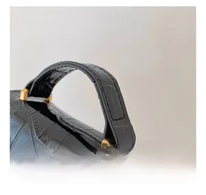 Close-up of black crocodile embossed leather handbag with gold metallic handle hardware