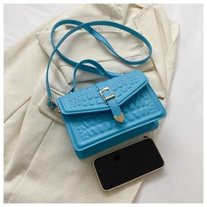 Detail of bright blue croc-effect square handbag with gold buckle and textured PU leather